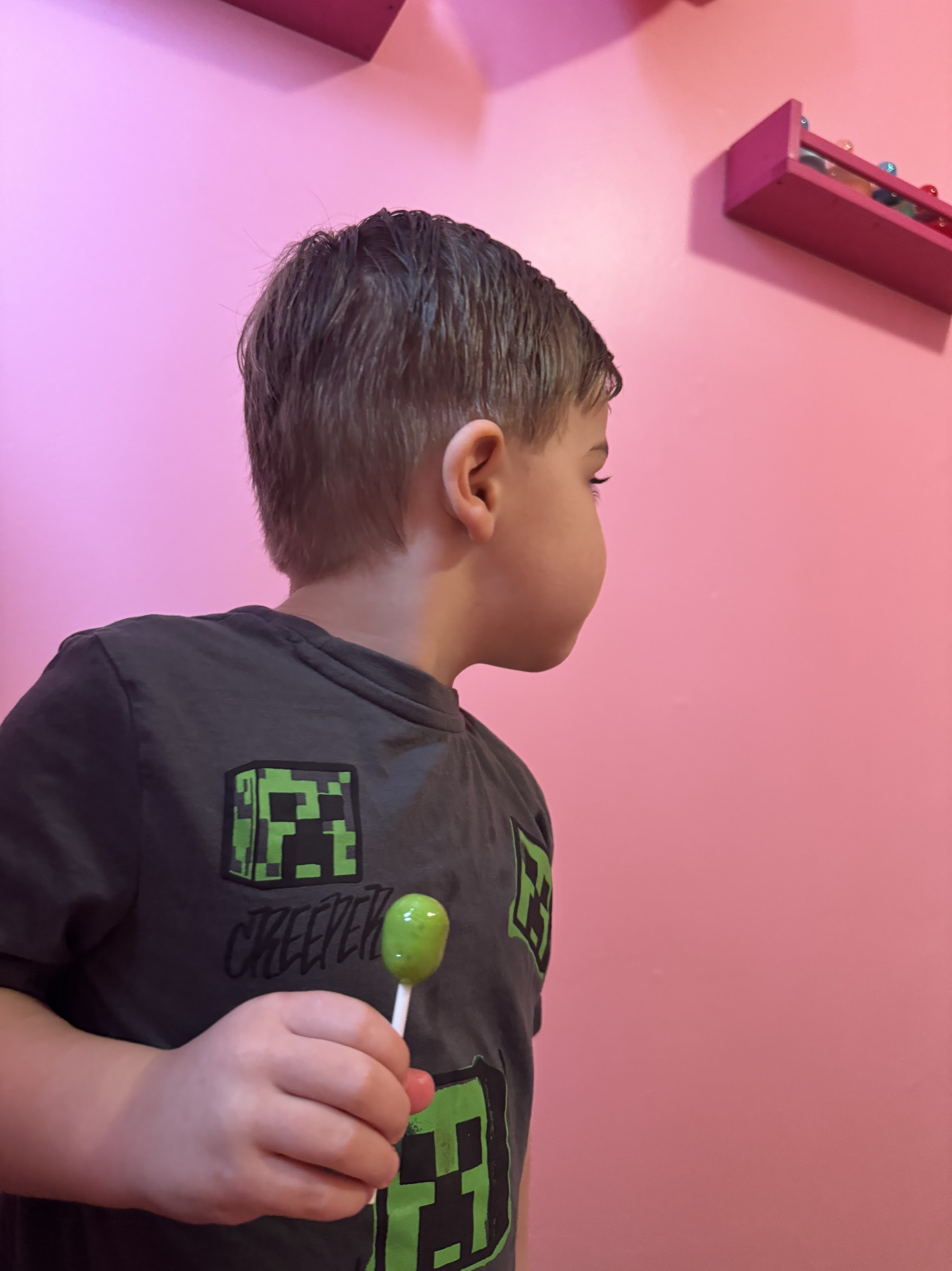 Young boy with a fresh cut holding a lollipop at Maryjo's Hair Design